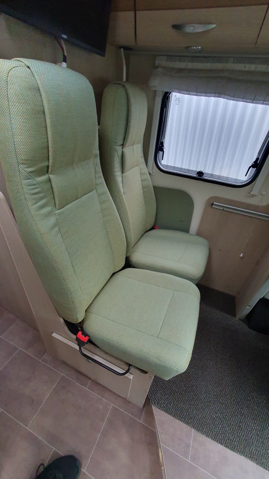 Grüne Wohnmobil-Sitze mit TV im Hintergrund