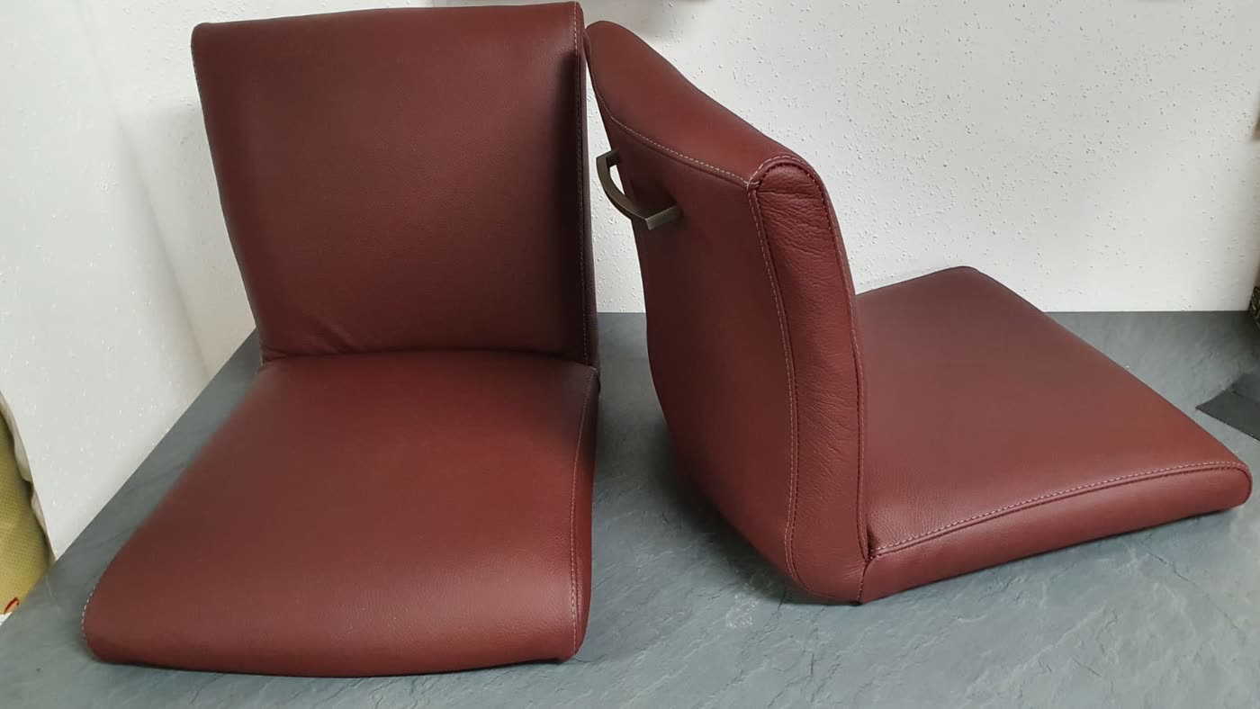 Zwei bordeauxfarbene Klappsitzkissen mit Metallgriff, vermutlich Fahrzeug