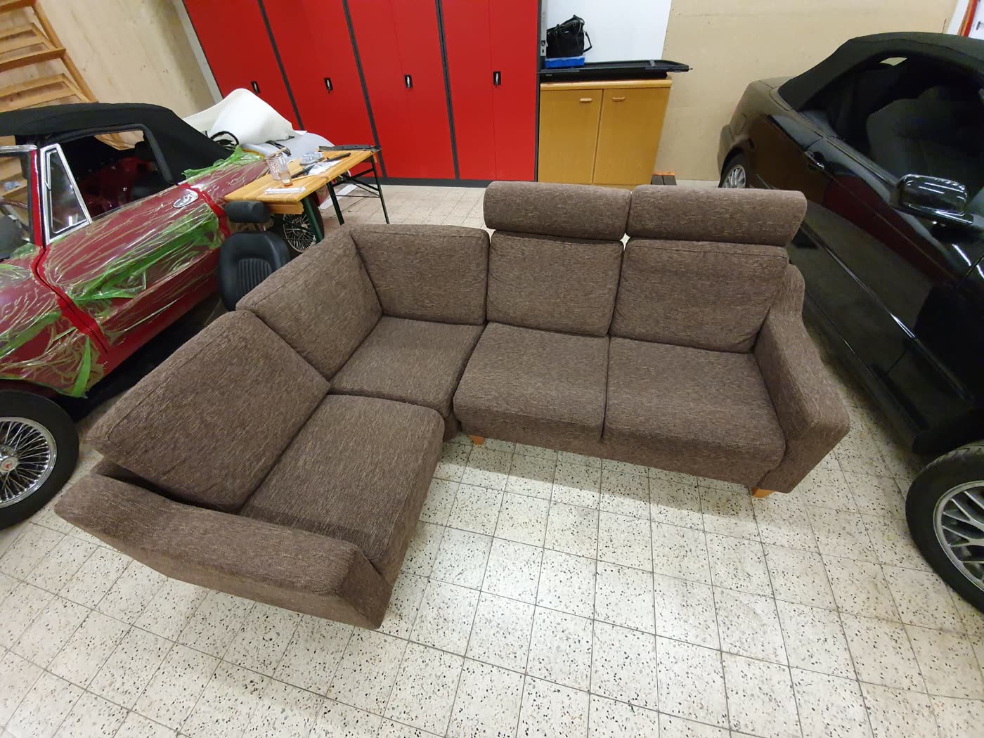Braunes Ecksofa, fertig, Werkstatt mit Oldtimern im Hintergrund