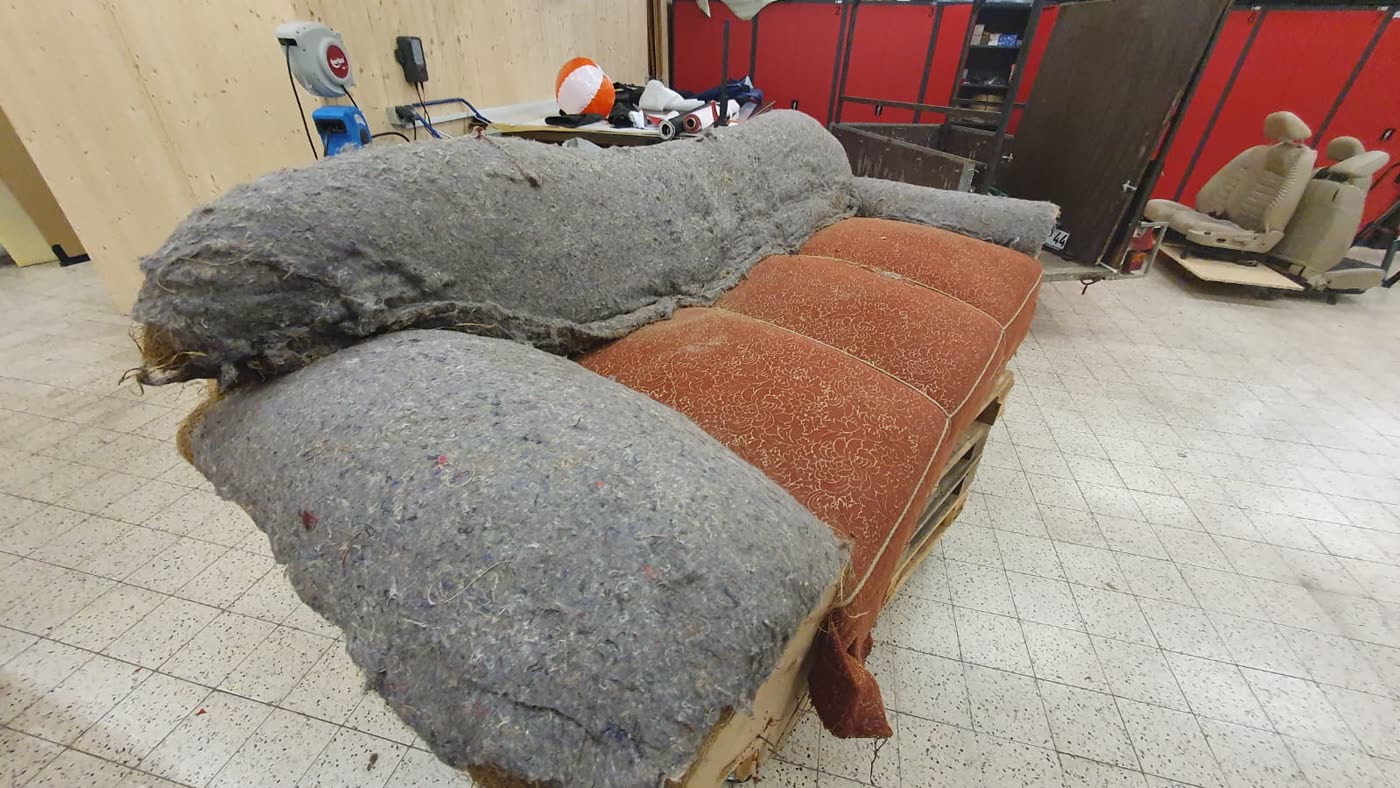 Altes rostfarbenes Sofa, ausgeschlachtet, graue Polsterwatte sichtbar