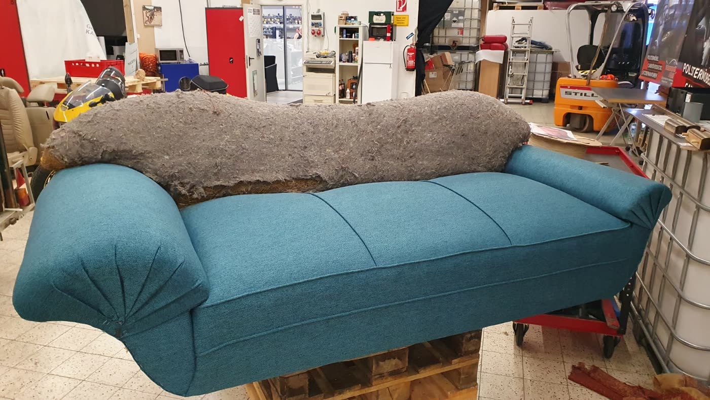Sofa halb bezogen, eine Seite petrol fertig, andere noch Rohwatte