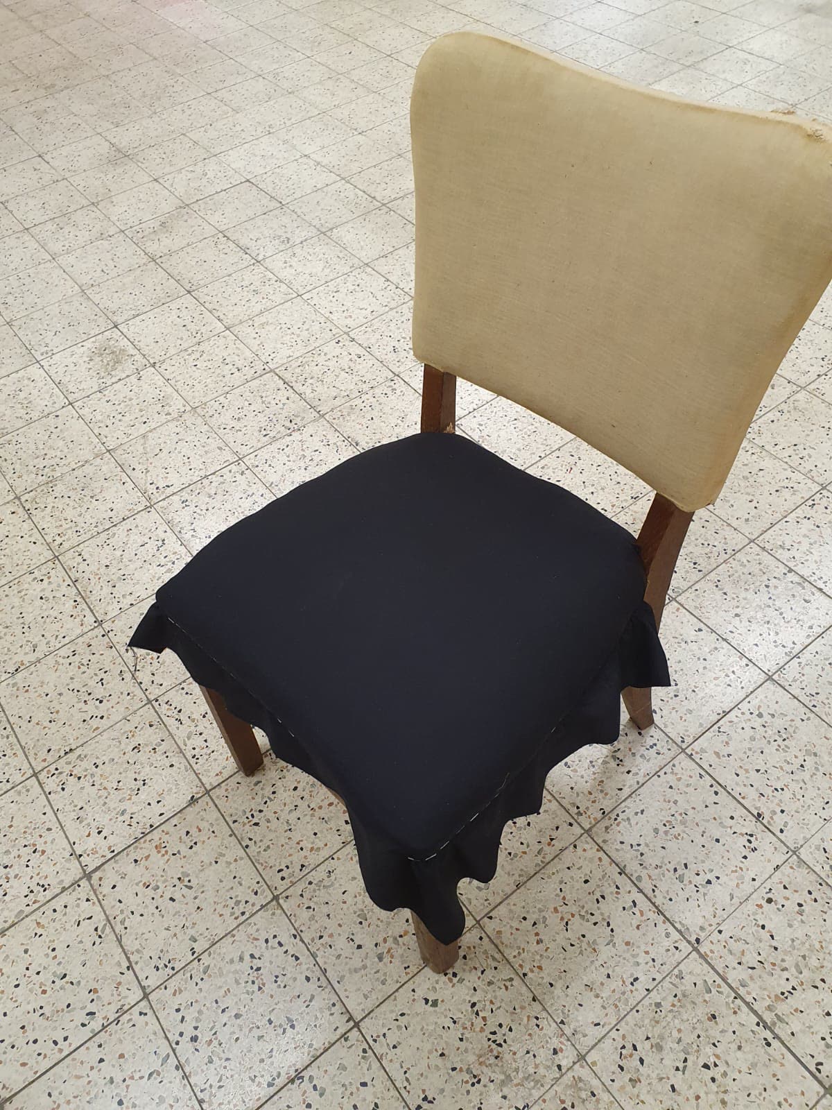 Abgenutzter cremefarbener Sessel mit schwarzem Stoff-Probestück