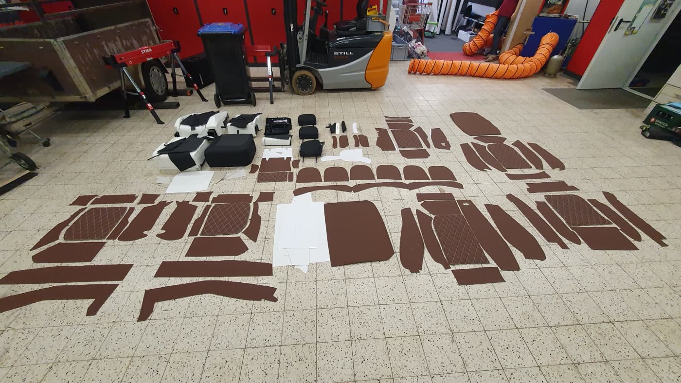 Viele zugeschnittene braune Lederteile am Werkstattboden